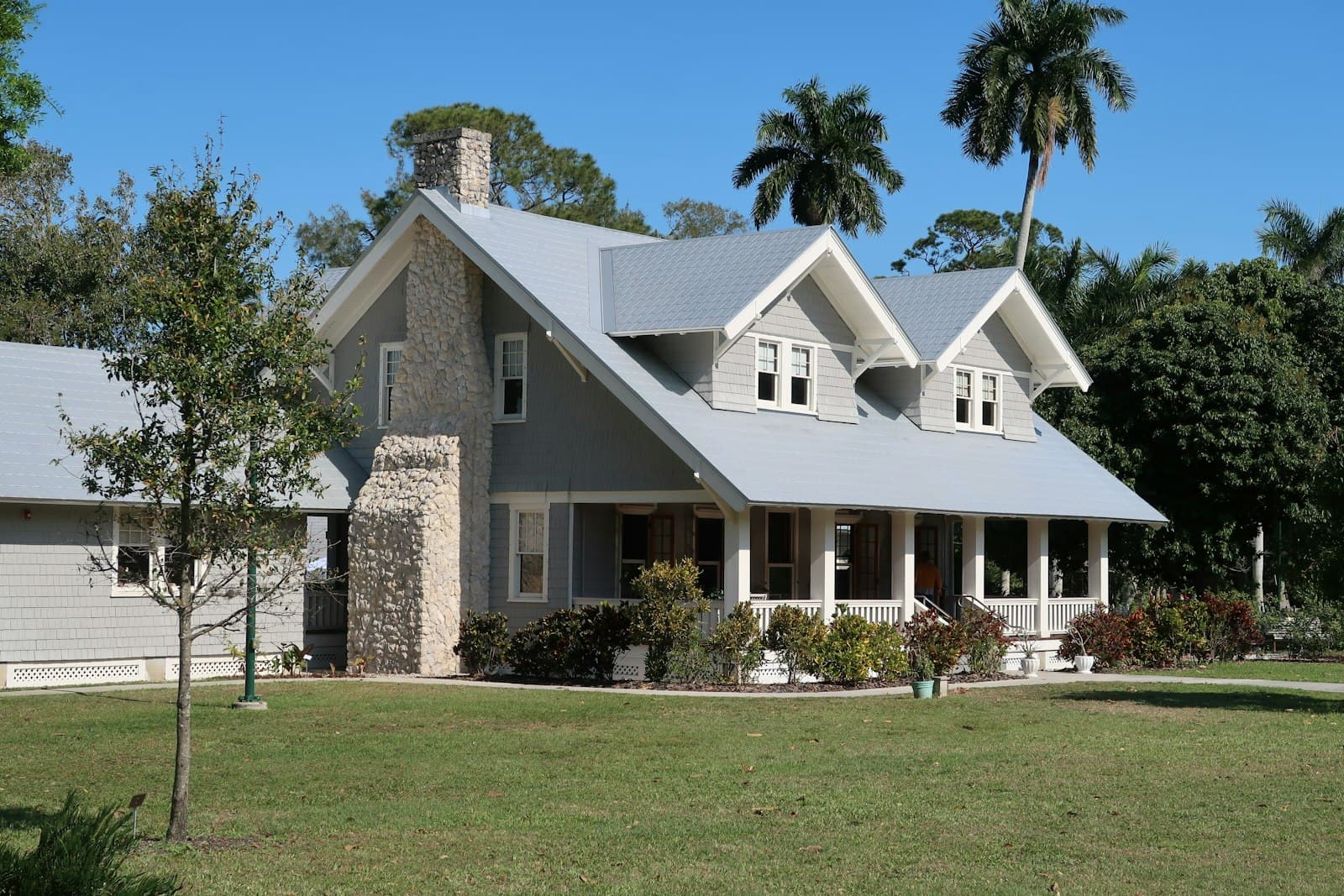 A welcoming rental home with a shaded front porch and a green garden