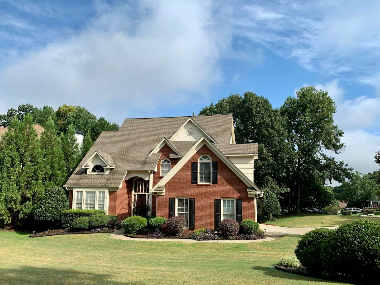 A two-storey red brick house with gabled dormers, behind a wide lawn
