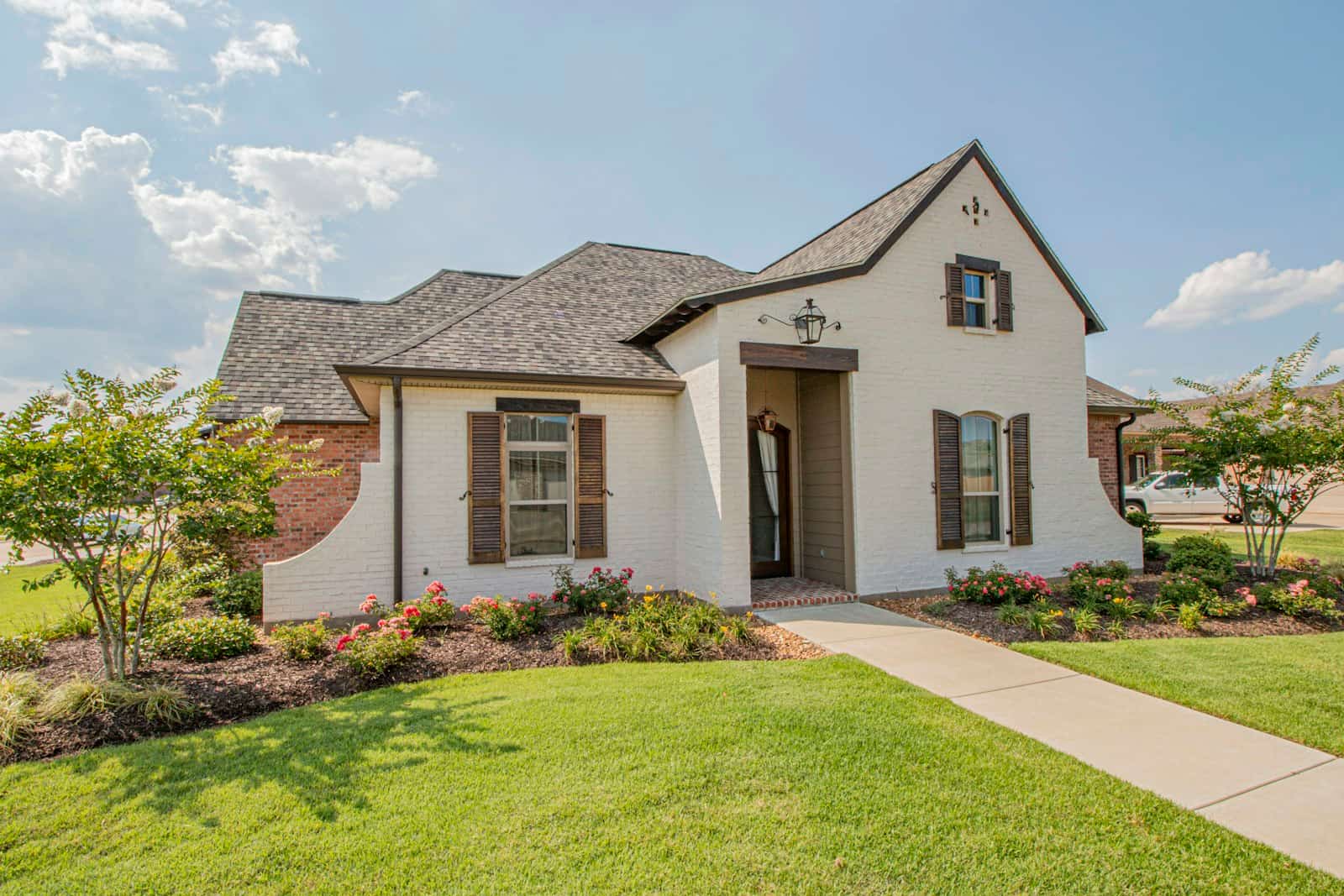 A white brick single-family house with a landscaped front garden